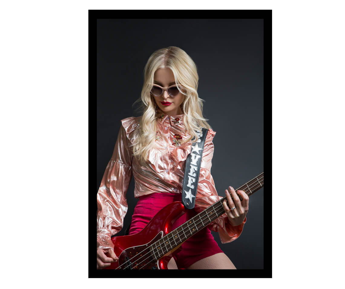 Jennie Vee playing the bass guitar while wearing her collaboration sunglasses by Valley Eyewear